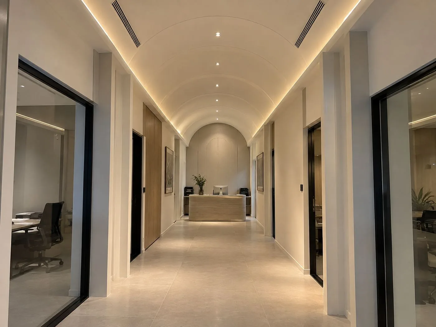 After: the same corridor finished — cove-lit barrel ceiling, glass partitions and laid flooring